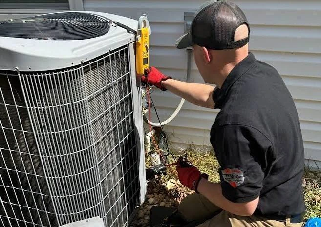 Technician in red gloves inspecting a residential outdoor air-conditioning condenser